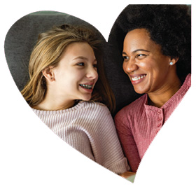 Heart-shaped framed close-up of a teenage girl and woman smiling at each other.