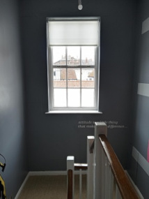 A photo of the half landing with a window looking outside. Carpeted stairs and painted walls.