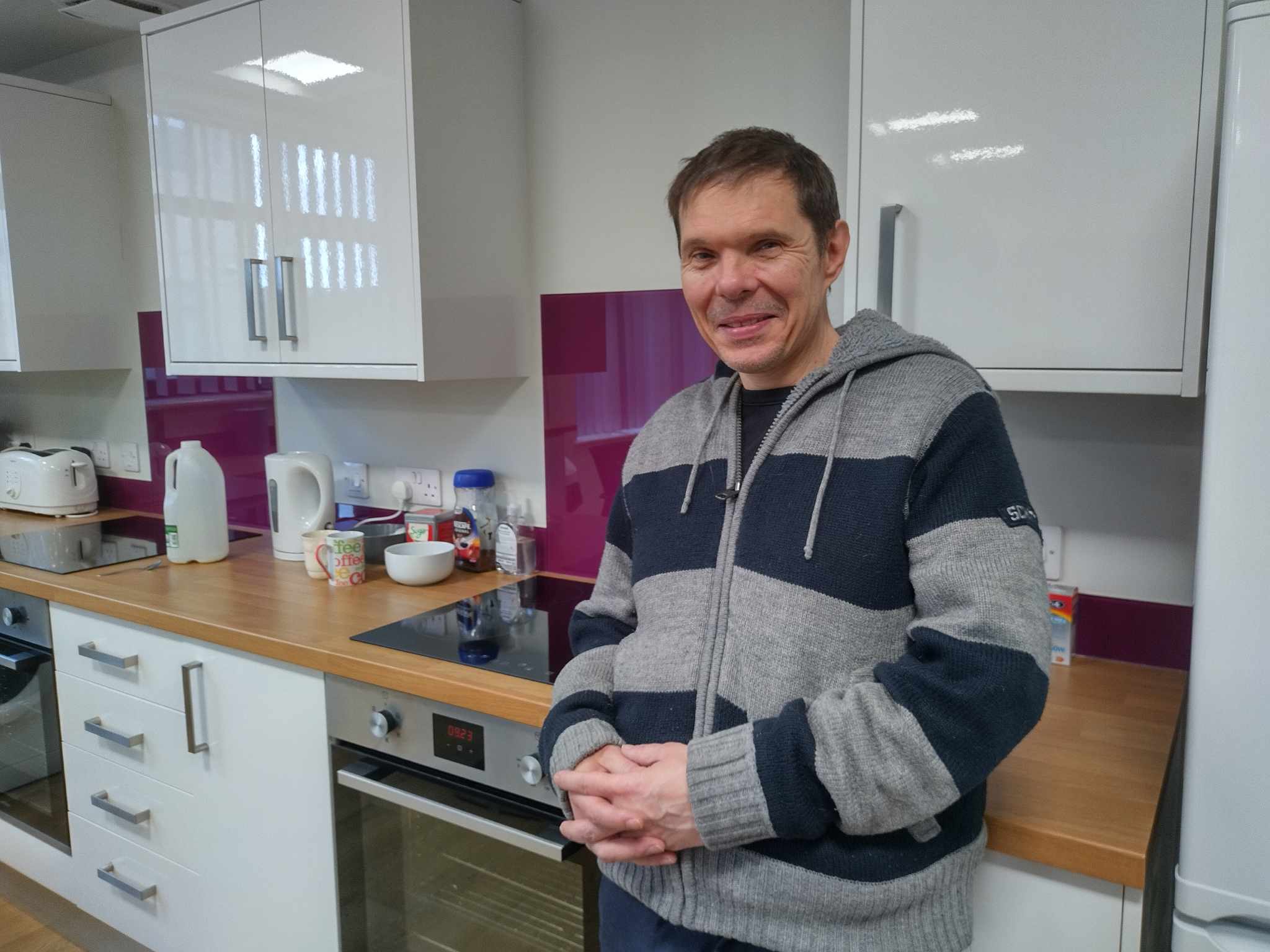 Man in a striped jumper stands in a kitchen