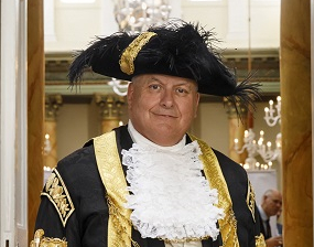 Head and shoulders of a man in black, white and gold mayoral dress