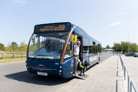 A passenger and his assistance dog exit a single decker Park and Ride bus using a ramp