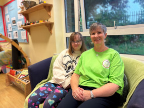 Young girl sat on a sofa next to a an adult