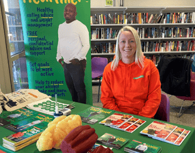 Health trainer Emma Scaling sitting behind a table at a drop-in at Tang Hall Explore