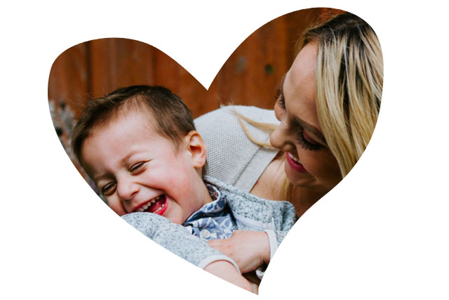 Heart-shaped framed close up photo of a woman and toddler giggling together.