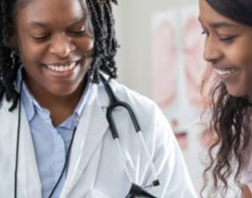 A close up of two doctors smiling while looking at something off screen.